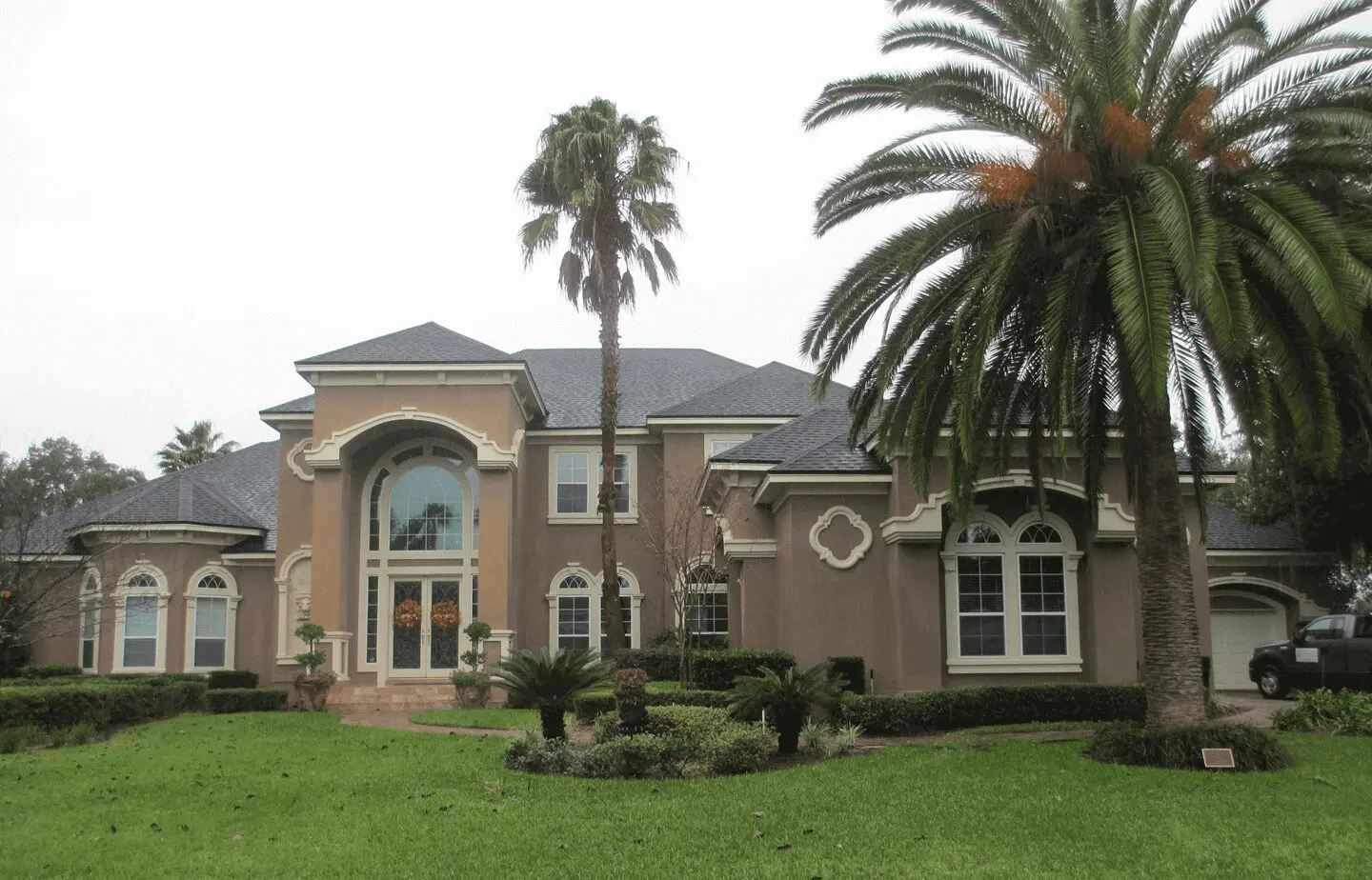 A large brown house with palm trees in front of it.