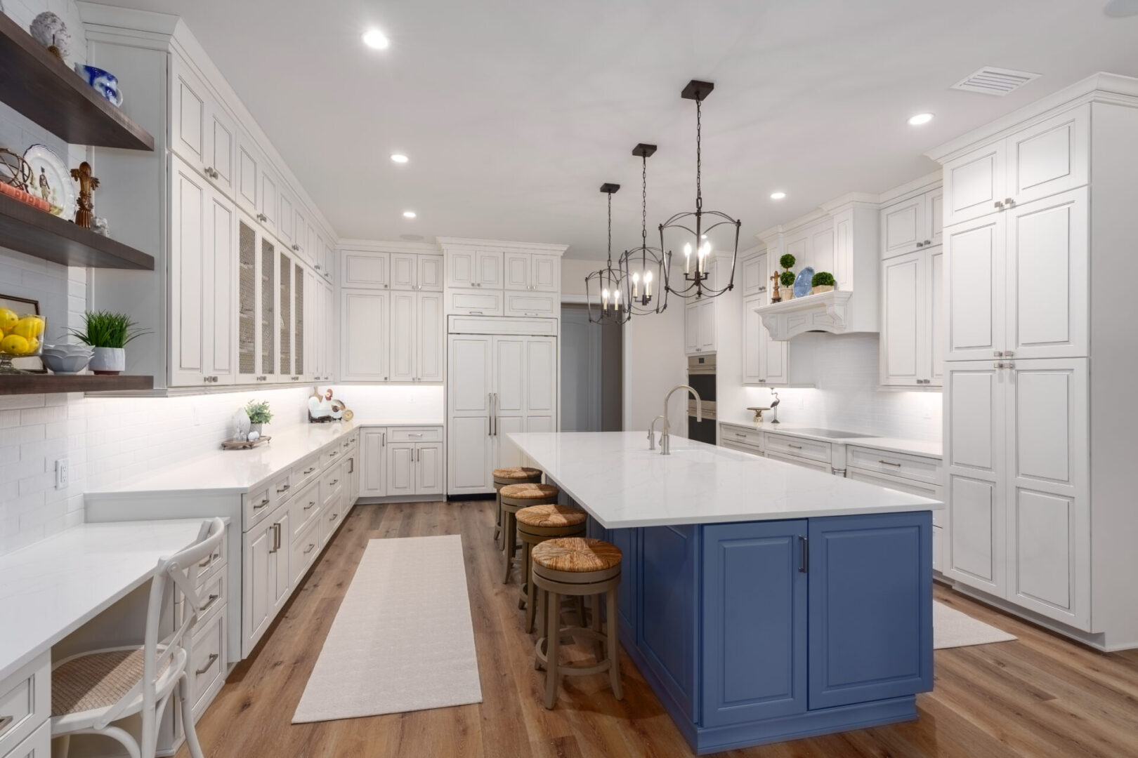 A kitchen with white cabinets and blue island.